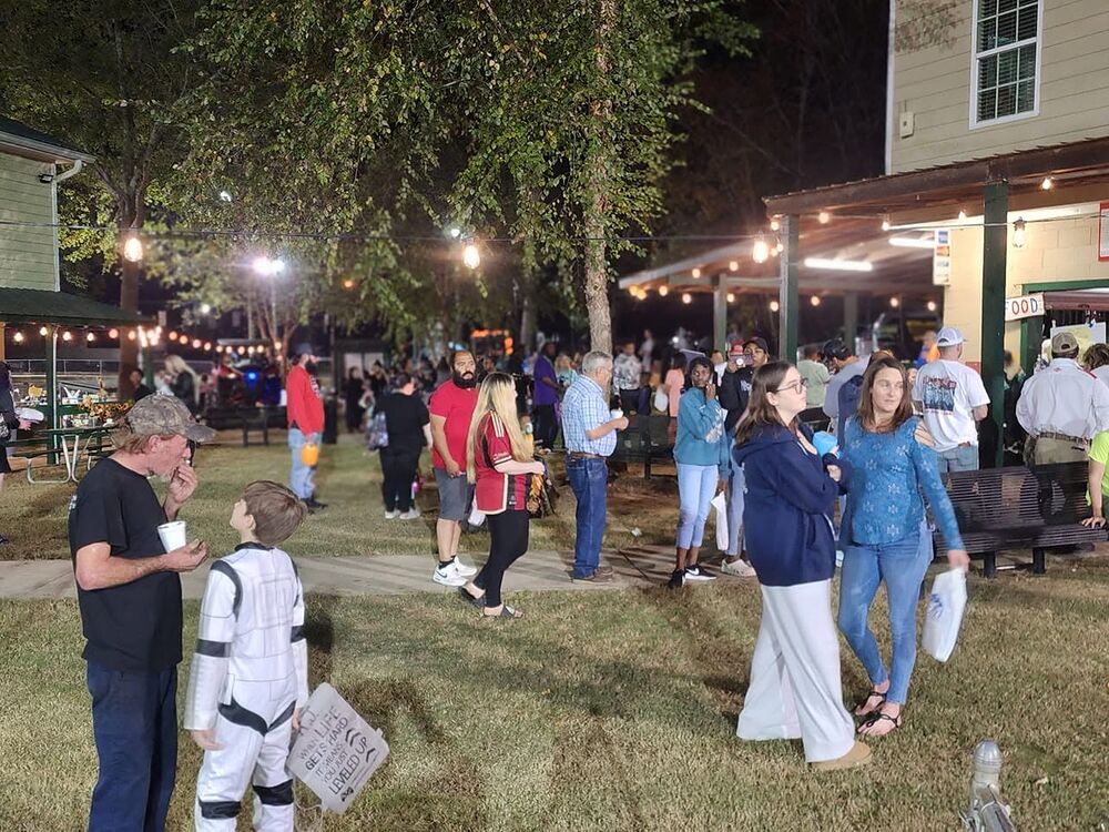 The Fall Festival in the evening, with string lights and people gathered by the food area